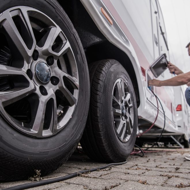 Caucasian Traveler Plugging Cables Into His Recreational Vehicle to Ensure Electricity Power. Camperground Stay During Traveling. Camper Handling Theme.